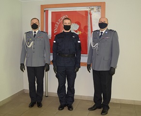 komendant zastępca komendanta i policjant stoją przy sztandarze