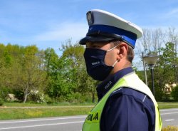 policjant ruchu drogowego w białej czapce i kamizelce obserwuje drogę