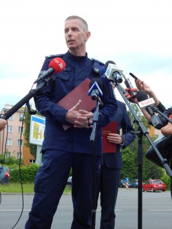 policjant w niebieskim mundurze stoi przed mikrofonem