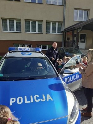 policjant z dziećmi stoi przy radiowozie