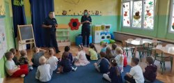 Policjant i policjantka rozmawiają z dziećmi w przedszkolu