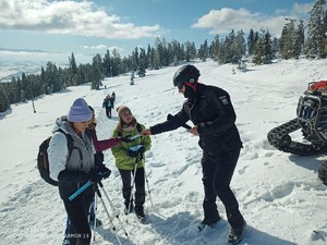policjant pochyla się nad dzieckiem i rozmawia z turystami w górach