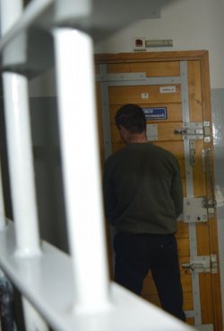zatrzymany stoi przed drzwiami pomieszczenia dla osób zatrzymanych