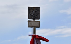 wierzchołek sztandaru na którym znajduje się godło polski z umieszczonym poniżej napisem policja