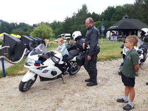 dziecko siedzące na motocyklu policyjnym, obok stojący funkcjonariusz