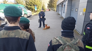 policjant z psem służbowym rozmawia z uczniami liceum