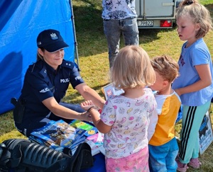 policjantka pokazuje chłopcu i dziewczynce kajdanki