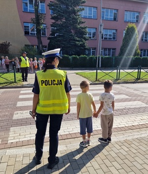 policjanci stoją z dziećmi w rejonie przejścia dla pieszych