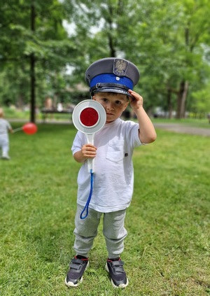 dziecko w policyjnej czapce z tarczą do zatrzymywania pojazdów w dłoni