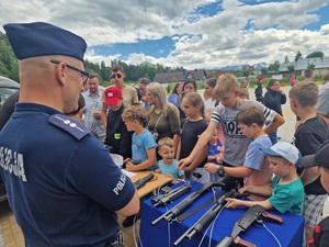policjant w mundurze a obok ludzie przy stoisku