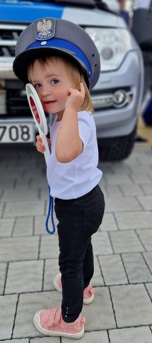 mała dziewczynka w czapce policjanta i lizakiem w dłoni
