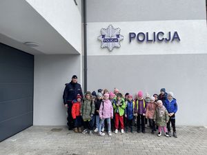Dzieci wraz z policjantem na tle budynku posterunku