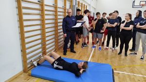 Kobieta lezaca na materacu obok stoi policjant
