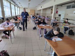 Dzieci piszące egzamin obok nich policjant