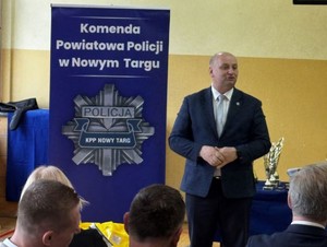 Mezczyzna w tle baner Komendy Powiatowej Policji w Nowym Targu