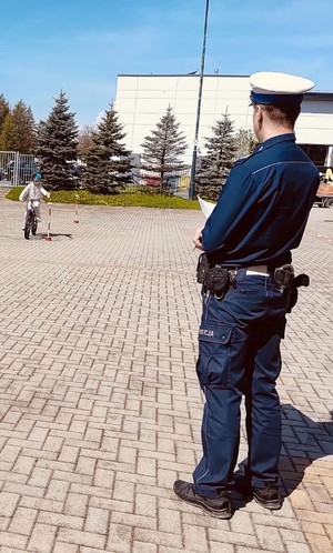 Policjant patrzący jak dziecko jedzie na rowerze