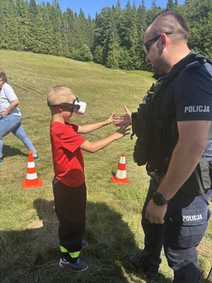 Policjant stojacy obok dziecka.
