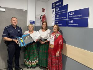 Kobiety w strojach góralskich stojące obok policjanta który trzyma w rękach alkomat