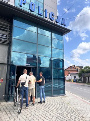Policjanci wraz z zatrzymanym złodziejem i rowerem stoja przed komenda