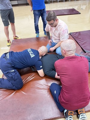 Policjant pokazujacy chwyt obezwładniający obok ratownicy