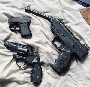 trzy sztuki broni położone na łózku