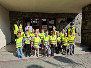 Zdjęcie grupowe dwójki policvjantów z dziecmi przed wejsciem do szkoły