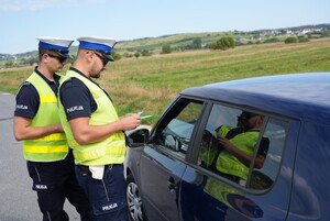 Dwóch policjantów stojących obok kontrolowanego pojazdu