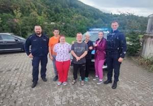 zdjęcie dwóch policjantów na tle radiowozu wraz z podopiecznymi z osrodka