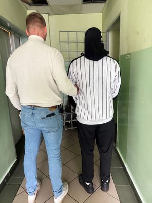 zatrzymany prowadzony przez policjanta ubranego po cywilu