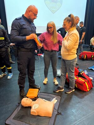 Policjant trzymajacy w rekach urzadzenie AED