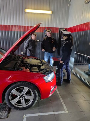 Policjantka i dwóch mezczyzn obok samochodu