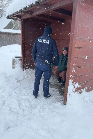 Policjant rozmawiający z mężczyzną na przystanku