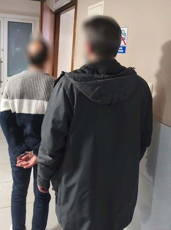 Dwóch mezczyzn jeden z nich ma załoozne kajdanki na rękach