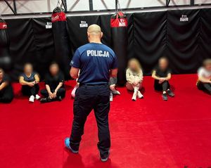 Policjant prowadzący wykład dla siedzących na macie kobiet