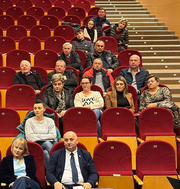 Grupa osób siedząc a w fotelach na sali widowiskowej