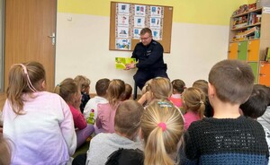 Policjant czytający bajke siedzącym na podłodze dzieciom