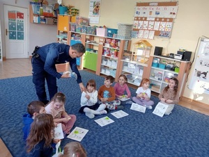 Policjant i grupka dzieci siedzace na dywanie