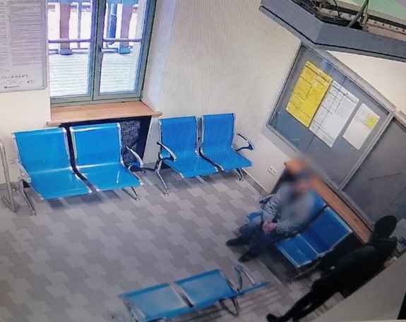 dwóch mężczyzn na poczekalni dworca jeden siedzi drugi stoi