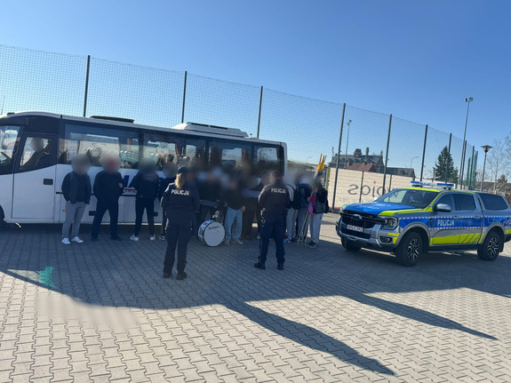 Kibice obok autobusu i radiowozu