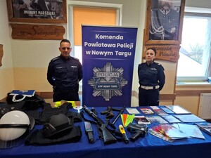 Policjant z policjantka obok baneru komendy