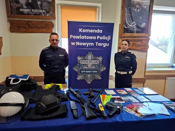 Policjant z policjantka obok baneru komendy