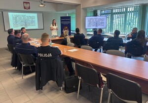 Kobieta w białej sukience i policjanci siedzący przy stołach