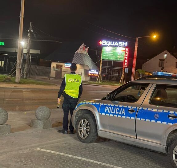 policjant stojący przed radiowozem