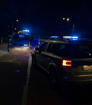 radiowóz i samochód w oddali z policjantem