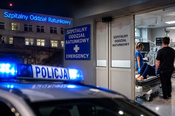 Zdjęcie na którym widoczny jest radiowóz i personel badający pacjenta