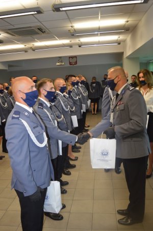 Komendant Powiatowy Policji młodszy inspektor Grzegorz Wyskiel wręczający nagrody funkcjonariuszom stojącym w szeregu