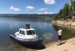 łódka policyjna i policjant na brzegu jeziora